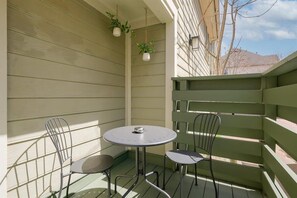 Eine kleine Terrasse im Freien mit einem runden Tisch und vier Stühlen, umgeben von einem grünen Holzzaun.