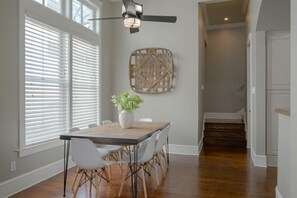 A dining area with a table, chairs, a ceiling fan, and a wall-mounted decorative piece. - Upscale Uptown Estate in Heart of Dallas (Dallas)