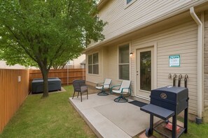 A backyard with a barbecue grill, outdoor seating, and a wooden fence. - Spacious 5-bd/3-ba Forest View Getaway (Dallas)