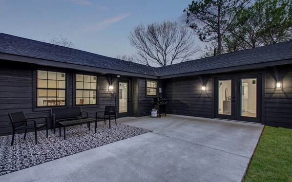 A modern building with a covered patio area featuring a seating arrangement and a concrete floor. - 3 Beds Houston Home, Close NRG Stadium & Rodeo (Houston)