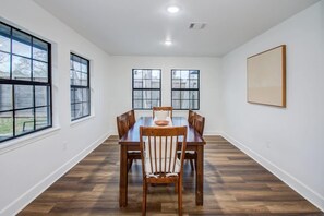 A dining room with a wooden table and chairs, large windows, and a white wall. - 3 Beds Houston Home, Close NRG Stadium & Rodeo (Houston)
