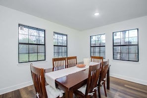A dining room with a wooden table and chairs, large windows, and a white interior. - 3 Beds Houston Home, Close NRG Stadium & Rodeo (Houston)