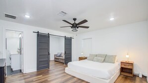 Une chambre avec un grand lit, un ventilateur de plafond et un placard à portes coulissantes.