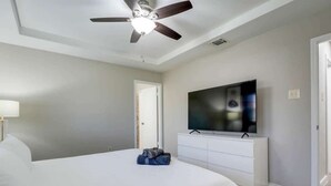 A bedroom with a bed, a ceiling fan, a TV, and a white dresser. - Texan Hideaway - Cozy, Convenient, Comfortable! (Lewisville)