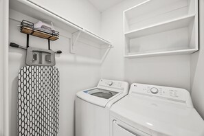 A laundry area with a washing machine, dryer, and ironing board. - Bright Modern & Cheerful 3bd/3ba, Medical District (Dallas)