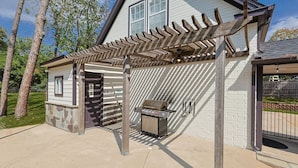 A covered outdoor area with a grill and a stone wall. - Your Rustic Retreat w Backyard Oasis, Pool, Patio (Roanoke)