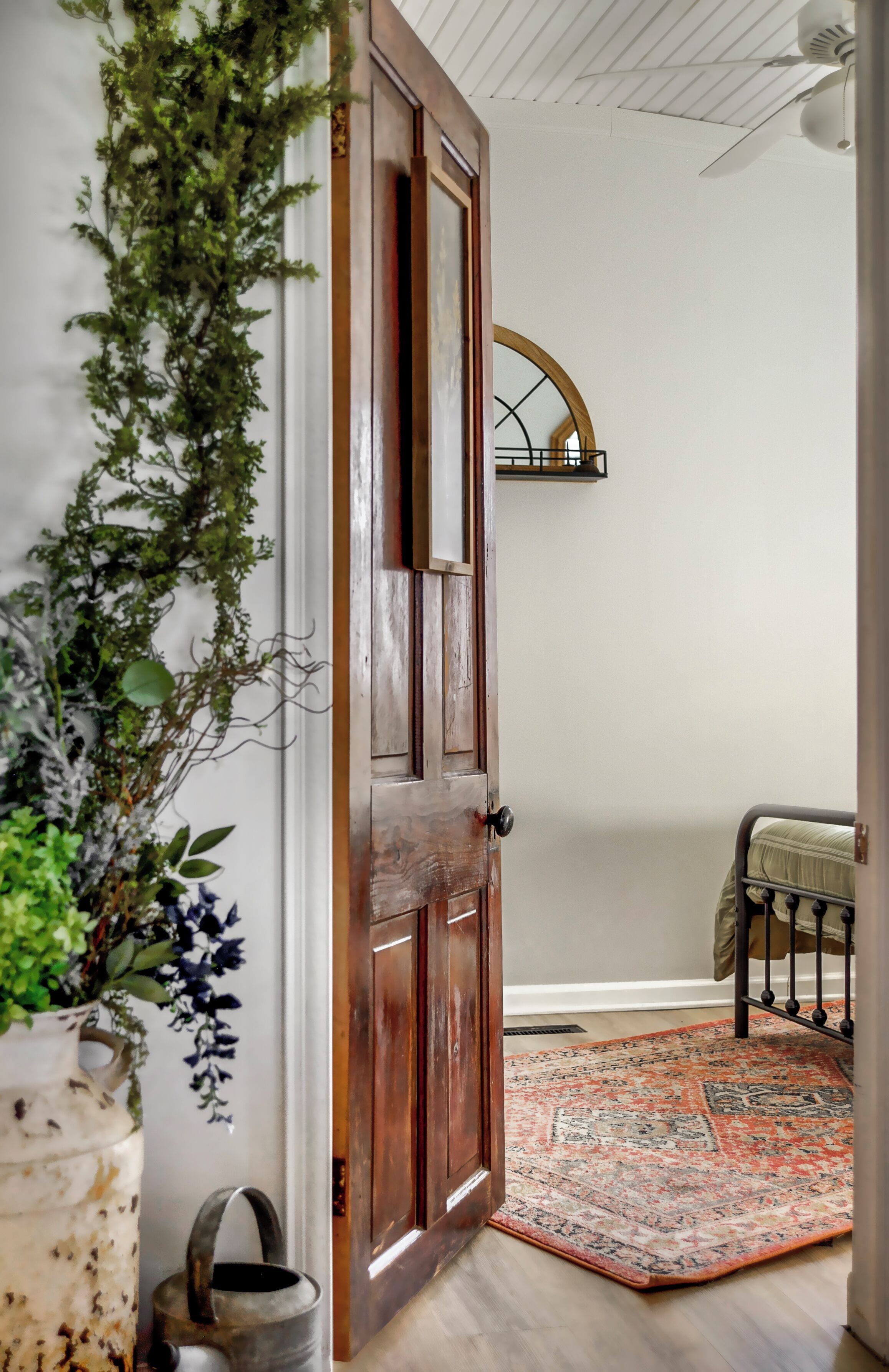 A wooden door with a white wall and a hanging plant.