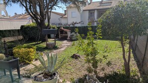 Ein Garten mit Blumentöpfen, einer Steinsitzbank und einem Weg.