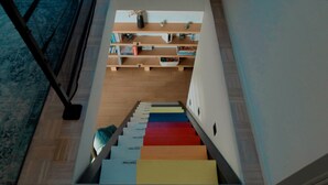 A staircase with colorful steps leading to a room with a bookshelf and a small plant. - Exceptional villa | Private pool and suites (Juville)