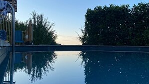 A clear pool with a reflection of trees and a building. - Exceptional villa | Private pool and suites (Juville)