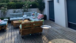 A deck with a sofa, wooden tables, and a small round table. - Exceptional villa | Private pool and suites (Juville)