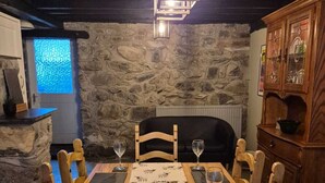 Ein Essbereich mit Holztisch, Stühlen und einer Wand aus Stein im Hintergrund.