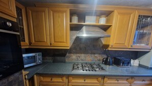 Eine Küche mit Holzausstattung, einer Mikrowelle, einem Gasherd und einer Kaffeemaschine.
