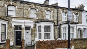 A row of terraced houses with white-framed windows and a black door. - Beautiful 3 Bedroom Flat in Fulham (London)