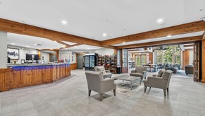 En rummelig lobby med en træreception, et loungeområde og udsigt til terrassen.