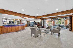 A spacious lobby with a wooden reception desk, seating area, and a view of the outdoor patio. - Two Bedroom, 2 Bath in the Heart of Breckenridge, Great Ski Access (Breckenridge)