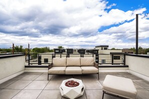 A rooftop terrace with a beige sofa, a hexagonal table, and a white ottoman. - Designer Rooftop Home on Tennyson (Denver)