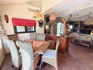 Ein Essbereich mit Korbstühlen, einem Holztisch und einem roten Vorhang.