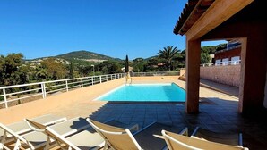 Ein Poolbereich mit Liegestühlen, einem Pool und Blick auf Hügel.