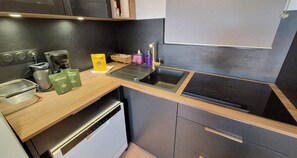 A compact kitchen with a coffee machine, a sink, and a dishwasher.