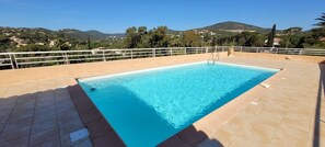 A rectangular pool with a clear blue water surface, surrounded by a tiled deck and a white railing.