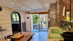 A modern kitchen with a wooden countertop, a green sink, and a view to an outdoor patio. - Completely renovated house with terrace and garden (Maisons-Alfort)