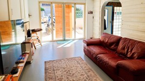 Una sala de estar moderna con un sofá de cuero rojo, una mesa de centro de madera y un ventanal con vistas a la calle.