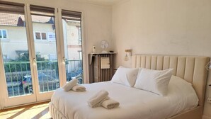 A bedroom with a large bed, a radiator, a fan, and a view through a sliding door. - Completely renovated house with terrace and garden (Maisons-Alfort)