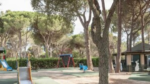 Une aire de jeux avec un toboggan, une balançoire et une structure d’escalade.
