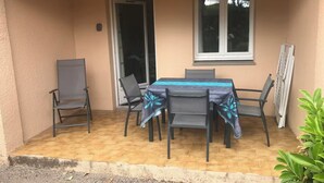 Une terrasse extérieure avec une table et des chaises, une porte-fenêtre coulissante et une fenêtre.