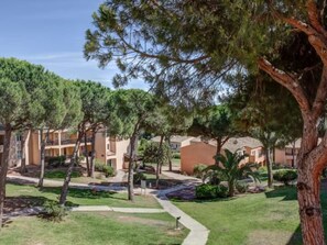 A courtyard with a pathway, trees, and multi-story buildings. - Studio in Saint-Raphaël: Pool & Tennis (Saint-Raphaël)