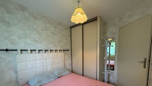 Una camera da letto con un letto, una testiera, un armadio, una porta e una lampada a sospensione.