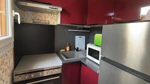 Cucina compatta con piano cottura, forno a microonde e frigorifero.
