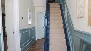 Eine Treppe mit blauen Geländern und beigem Teppich, die zu einer Tür mit einem Spiegel darüber führt.