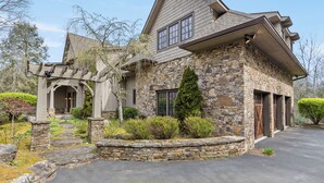A stone house with a stone porch, a garage, and a well-maintained garden. - 5-bedroom 3-Story Home w/ 3 Car Garage In Gated Community +Pool Table +Huge Deck (Highlands)