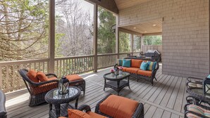A covered outdoor deck with wicker furniture, a glass table, and a barbecue grill. - 5-bedroom 3-Story Home w/ 3 Car Garage In Gated Community +Pool Table +Huge Deck (Highlands)
