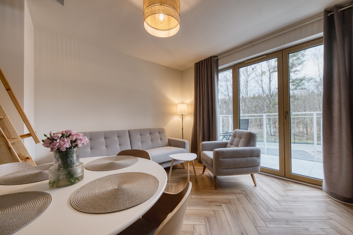 A modern living room with a sofa, armchair, and a dining table with placemats.