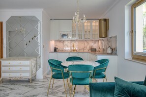 Una cocina moderna con armarios blancos, encimera de mármol y una araña.