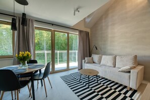 Una sala de estar moderna con sofá, mesa de comedor, sillas y un amplio ventanal con cortinas.
