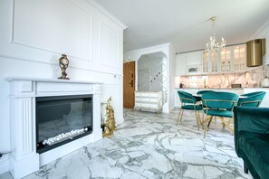 Una cocina moderna con pisos de mármol, gabinetes blancos y un comedor con sillas tapizadas en verde.