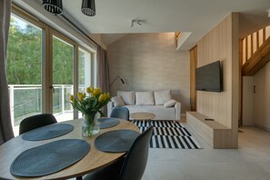 Una sala moderna con sofá, televisión y comedor con individuales.