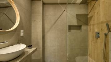 Un baño moderno con un lavamanos ovalado grande, un espejo, ducha con puerta de cristal y una pared de acento de madera.