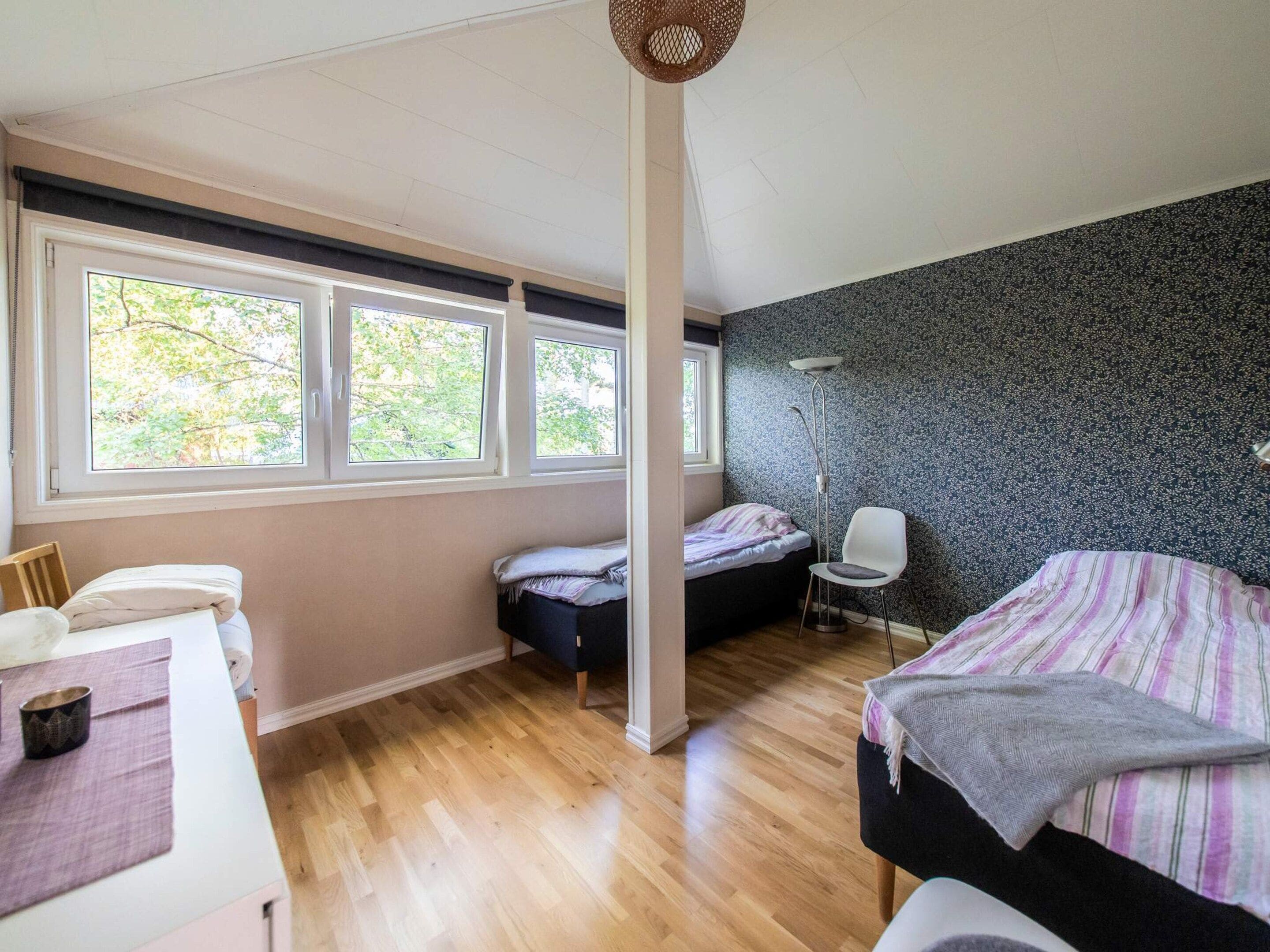 A bedroom with a bed, a chair, a desk, and a window with a view of trees.
