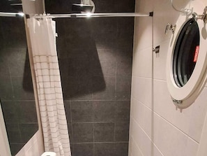 Une salle de bain Ă©quipĂ©e dâun rideau de douche, de toilettes et dâun bidet fixĂ© au mur.