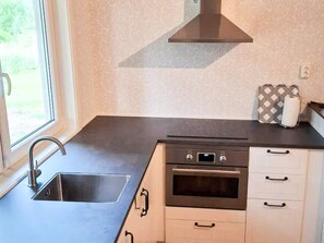 Una cocina con un lavamanos de acero inoxidable, horno empotrado y ventana que proporciona luz natural.