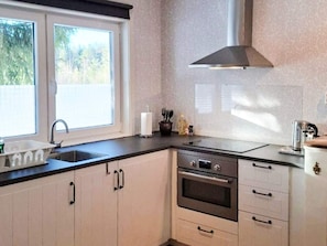 A kitchen with a window, sink, stove, and cabinets.