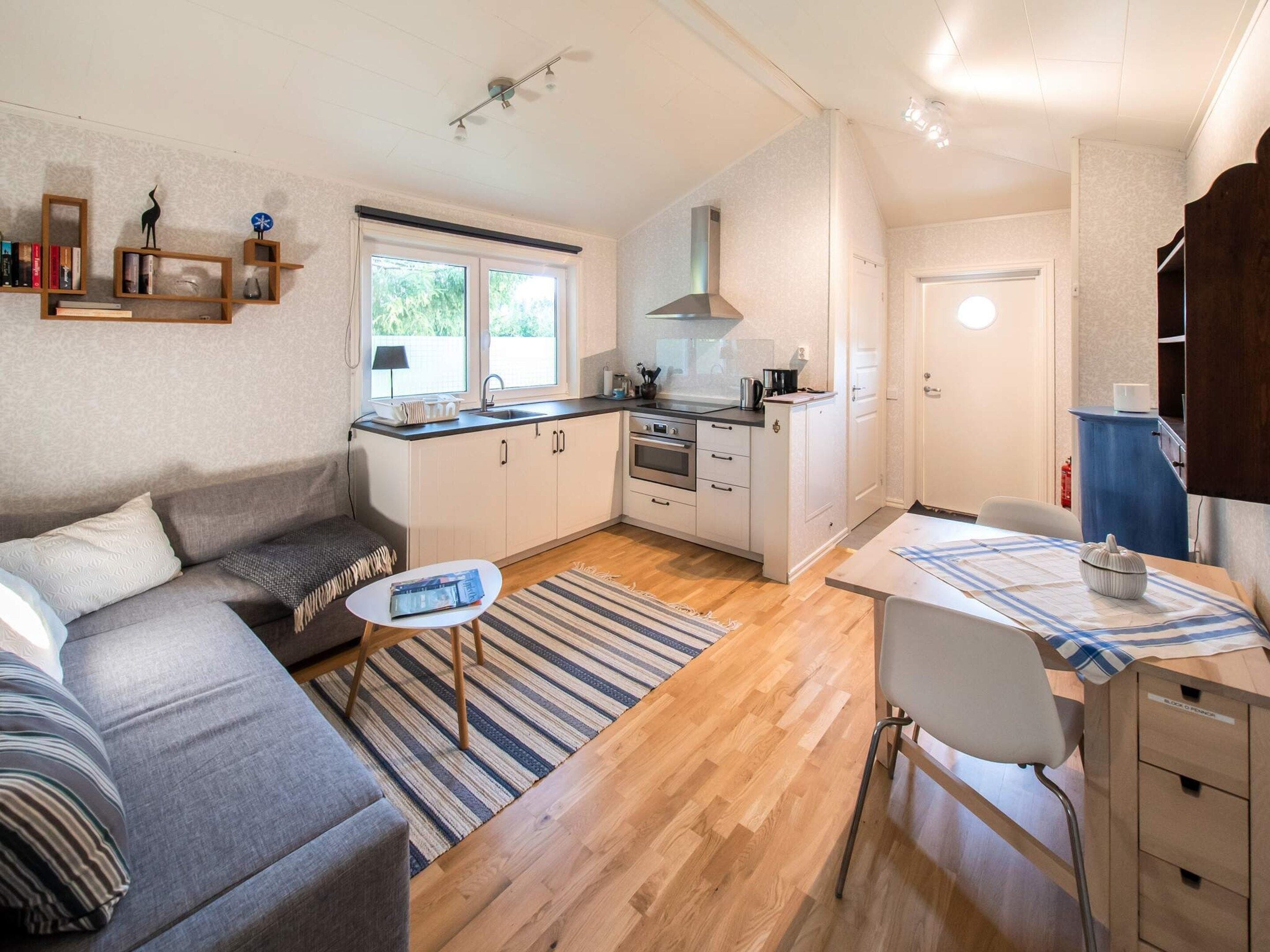 A compact living space with a kitchenette, a sofa, a dining table, and a small rug.