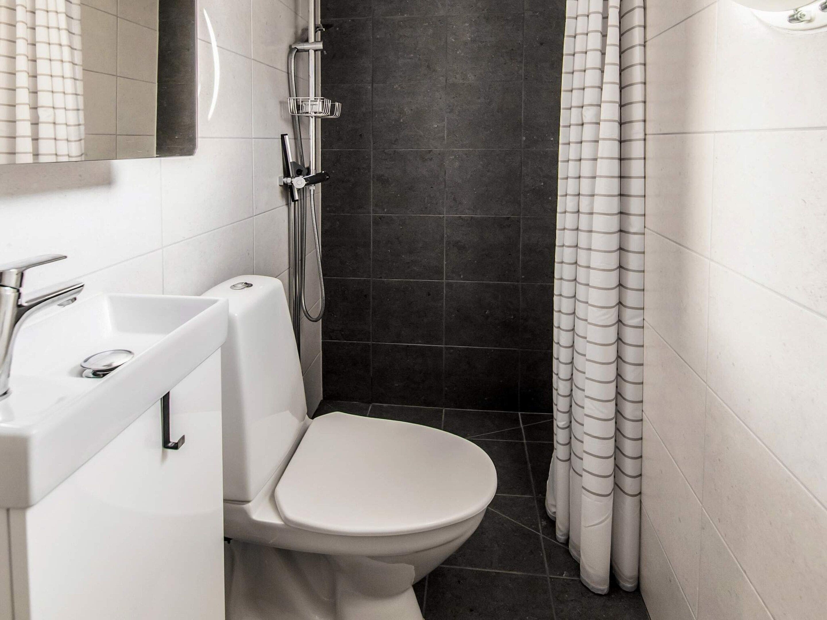 A bathroom with a white toilet, a sink, and a shower area.