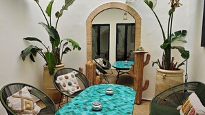 A dining area with a round table, chairs, and potted plants. - Riad 3 rooms, medina, Top Location (Marrakech)