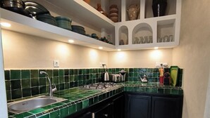 A kitchen with green tiles, a gas stove, a sink, and shelves with kitchenware. - Riad 3 rooms, medina, Top Location (Marrakech)
